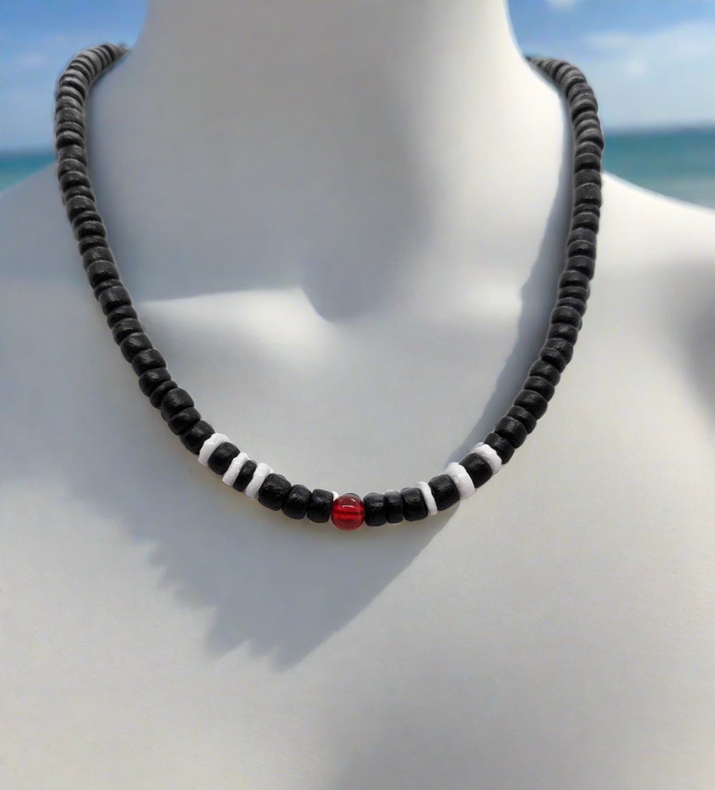 Black wooden beaded necklace, with white wooden beads and a red accent beads.