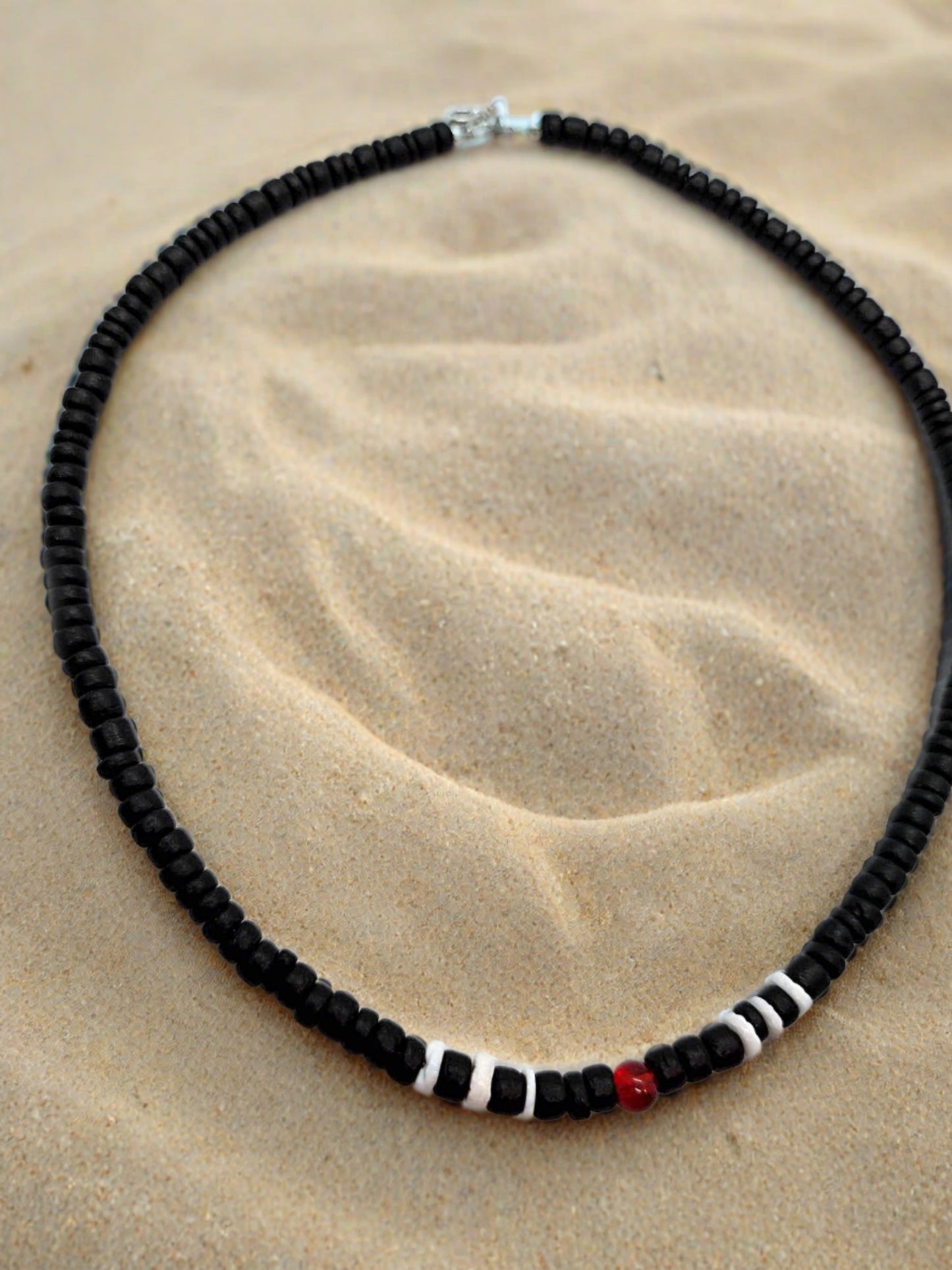 Our black wooden beaded necklace with white wood beads and a red glass bead for accents.