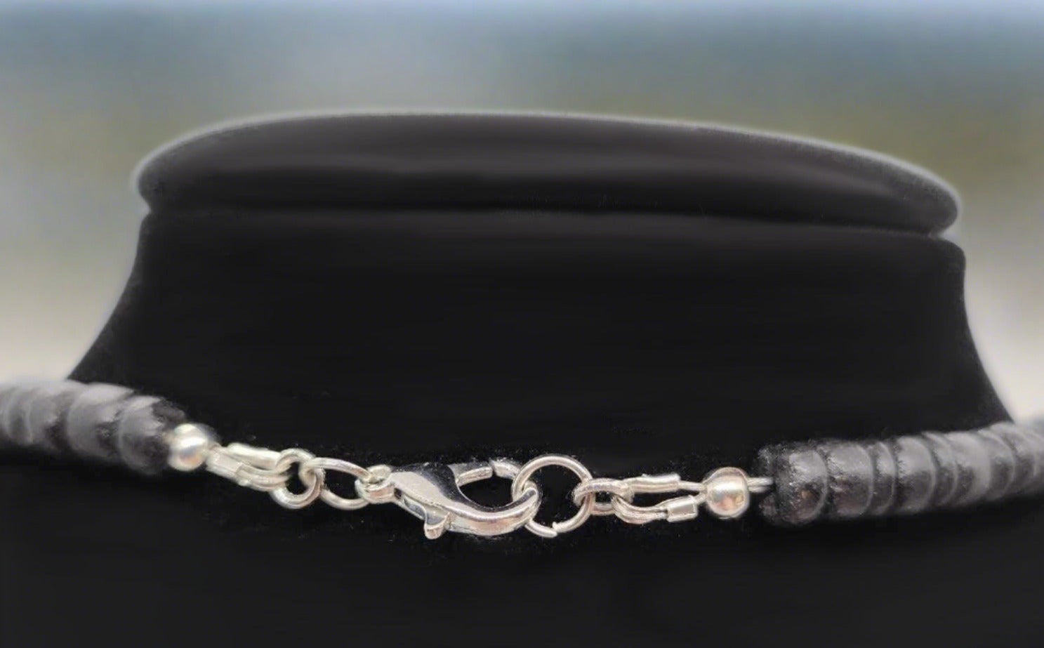 A close up of the sliver tone alloy metal lobster claw clasp .