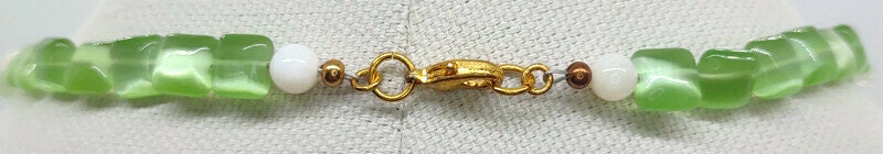 Close up of the gold tone lobster claw on the apple green nacklace.
